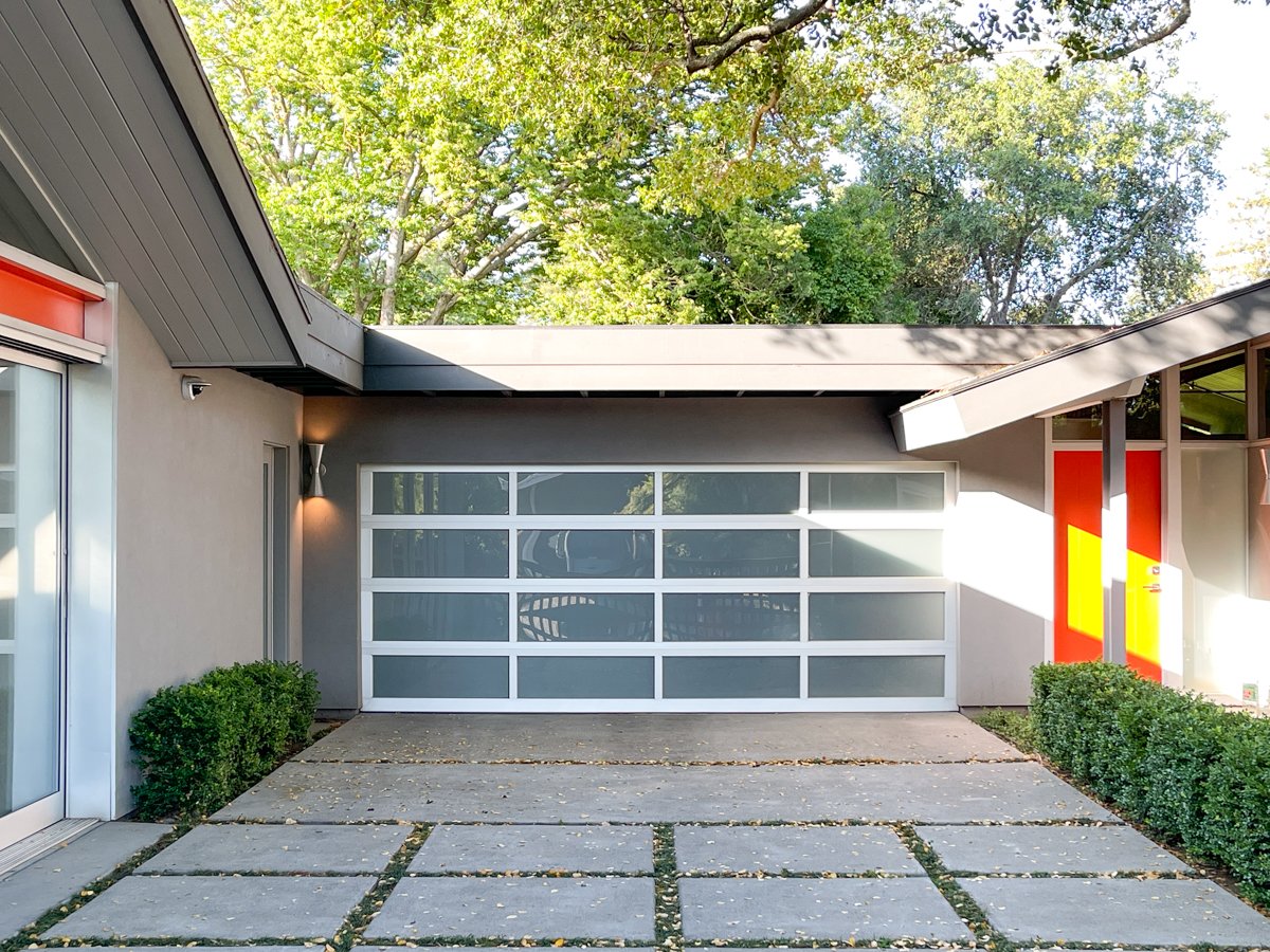 Modern home with glass panel garage door and concrete driveway
